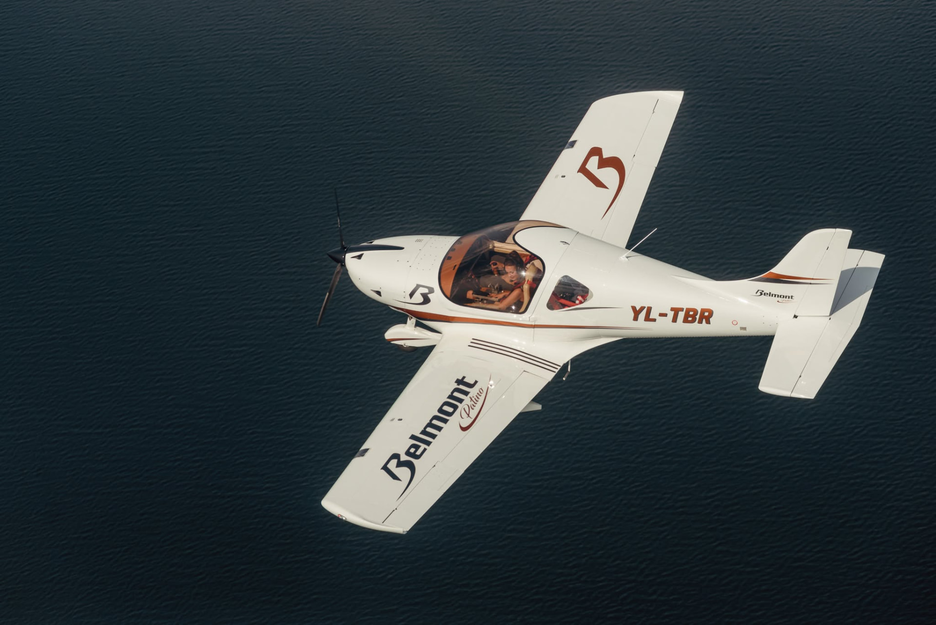 White Belmont YL-TBR banking over dark water in flight